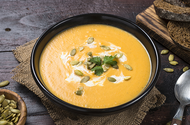 Pumpkin cream soup on dark wooden table.